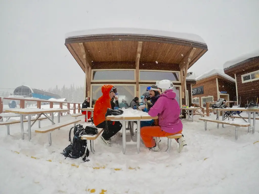 skiers taking a break at a picnic table on a snowy day